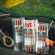 Load image into Gallery viewer, Three packages of Hickory BBQ Beef Sticks on a truck dashboard background