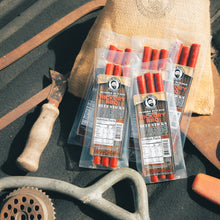 Load image into Gallery viewer, Beef sticks in packaging with a rustic background featuring a knife and grinder.