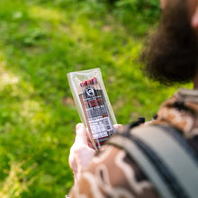Load image into Gallery viewer, Person holding a package of beef sticks outdoors with green grass in the background
